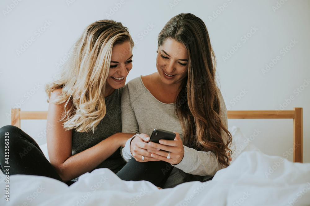 Sticker Girls playing with a phone in bed