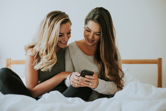 Girls playing with a phone in bed