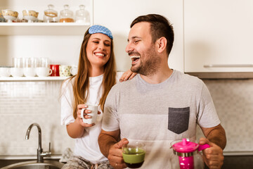 Young couple drinking hot coffee in kitchen in the morning.