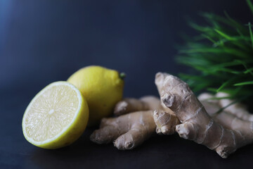 Ginger root whole and sliced. Ginger tea with lemon on the dark background. Fresh ginger root on stone background. Vitamins. Free space for your text.