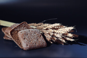 Fresh loaves of bread with wheat and gluten on a black table. Bakery and grocery concept. Fresh, healthy sorts of rye and white loaves food closeup. Fresh homemade bread with cereals.