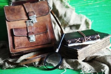 Old leather bag with a magnifying glass on a brown traveler wooden table background with copy space.