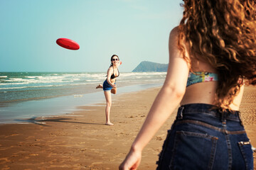 Women are playing frisbee at the beach - Powered by Adobe