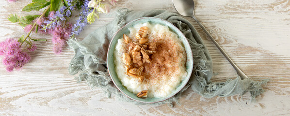 flat lay of a bowl of rice porridge with cinnamon and nuts on a light table