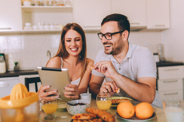 Young couple websurfing with tablet in home kitchen