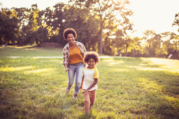  African American mother and daughter running trough park. Focus on little girl. - 435363865