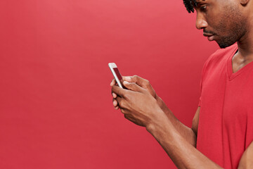 Detail black man in red t-shirt using a mobile phone on red background