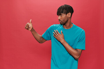 Smiling black man with green t-shirt making positive hand gesture on red background