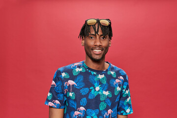 Smiling black man with patterned t-shirt and sunglasses on his head looking at camera