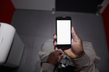 Top view closeup of unrecognizable African-American man using smartphone while sitting on toilet in...