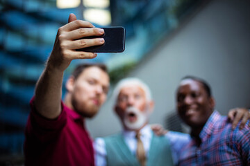  Three business men standing outside and using mobile phone.