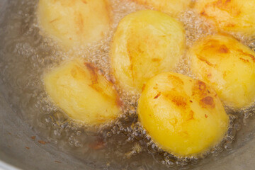 Golden potatoes are fried in boiling oil in a cauldron