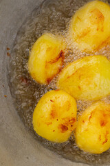 Golden potatoes are fried in boiling oil in a cauldron
