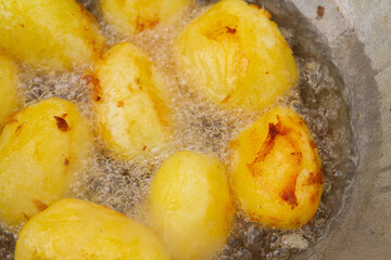 Golden potatoes are fried in boiling oil in a cauldron