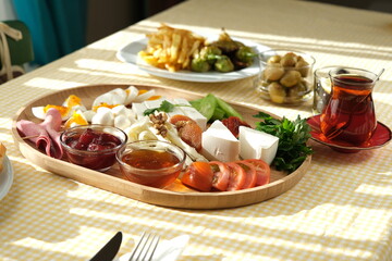 Delicious traditional turkish breakfast on yellow checkered tablecloth.
Tea, olives, eggs, cheeses, cucumbers, tomatoes,
French fries and peppers