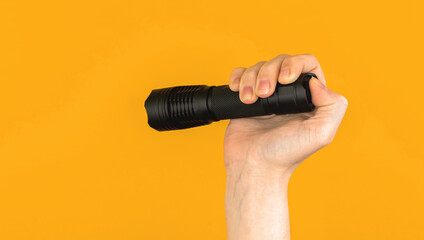 Woman hand holds black EDC flashlight on bright colorful backgroundm equipment outdoor concept - obrazy, fototapety, plakaty
