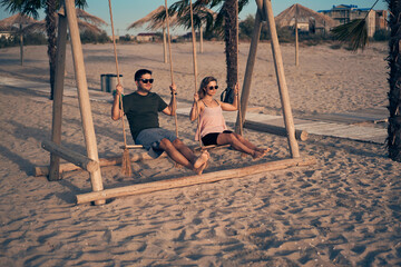 Young attractive couple swinging on seesaw on the beach.