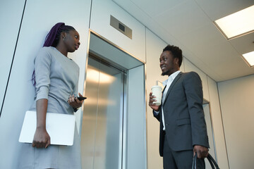 Low angle view at two African-American business people waiting for elevator in office building and chatting © Seventyfour