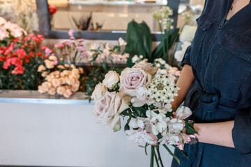 Female hands hold bouquet of flowers. Light beige roses. Concept flowers as gift for anniversary