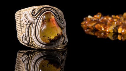 Luxurious beige leather bracelet with sparkling yellow amber on a black background with reflection. Baltic amber stone with plant inclusion, Slavic culture, isolated amber jewelry. 