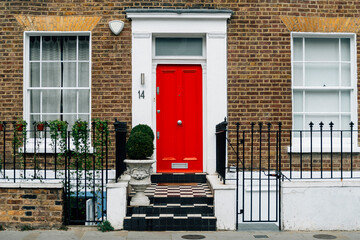 Red colored front door of a city house - Powered by Adobe