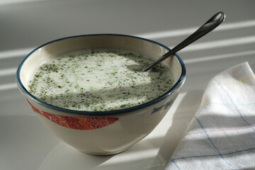 Peppermint tzatin and spoon in a bowl on a white background