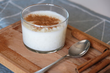 Rice pudding with cinnamon in glass bowl on wooden stand