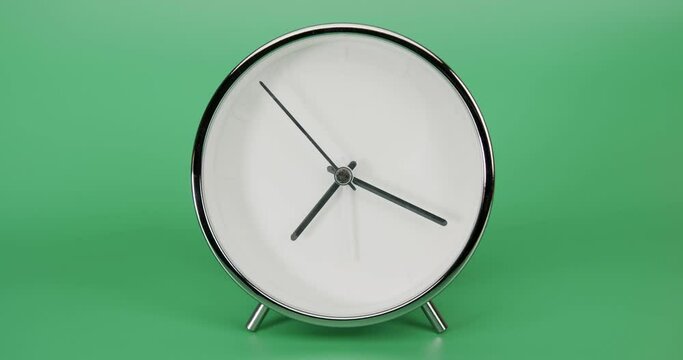 Silver Alarm clock isolated on green background, Time starts walking at 7 o'clock, Time lapse 5 hour.
