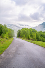 the road leads to the mountains which are covered with fog.