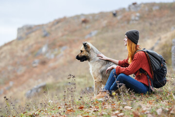 cheerful woman hiker in the mountains outdoors next to the dog travel vacation
