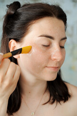 Woman makes beauty treatments at home. Woman applies scrub to her face. 