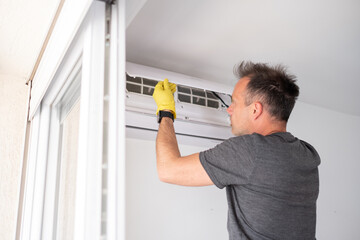 man in yellow gloves opening air conditioner