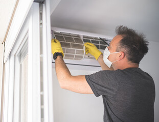 man wearing a protective mask and cleaning air conditioner