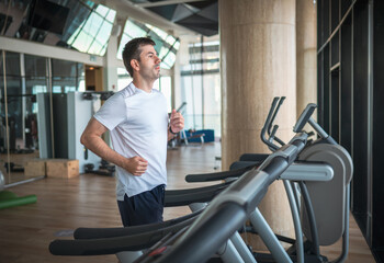 Fototapeta na wymiar Man jogging on a treadmill during a cardio running warmup exercise in the gym