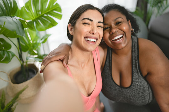 Young Latin women taking selfie with smartphone cam while doing yoga and pilates at home - Sport wellness lifestyle concept