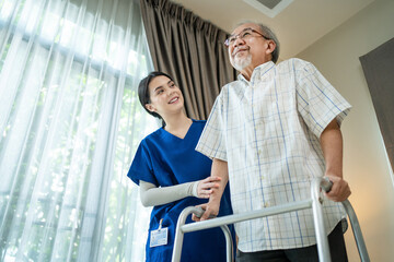 Asian nurse helping old man to practice walking by using 4 legged cane