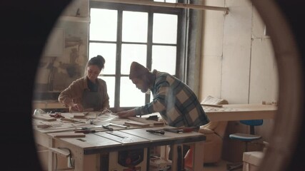 Lockdown of two joiners standing at workbench in joinery workshop and working with wood together. Carpentry courses