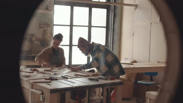 Lockdown of two joiners standing at workbench in joinery workshop and working with wood together. Carpentry courses