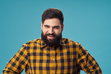 Obraz premium a man with a beard and a plaid shirt holds his hands on his belt on a blue background