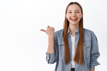 Hey check this out, logo here. Smiling pretty teenage girl with long healthy hair smiling, pointing...