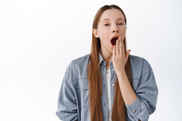 Tired or bored teenage girl student, yawning and looking indifferent sleepy, standing in casual clothes against white background