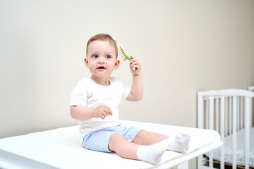 Fototapeta premium a small child with blue eyes holds a comb in his hands