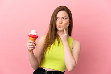 Teenager girl with a cornet ice cream over isolated pink background having doubts while looking up