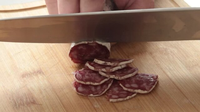 gros plan sur la coupe d'un saucisson avec un couteau