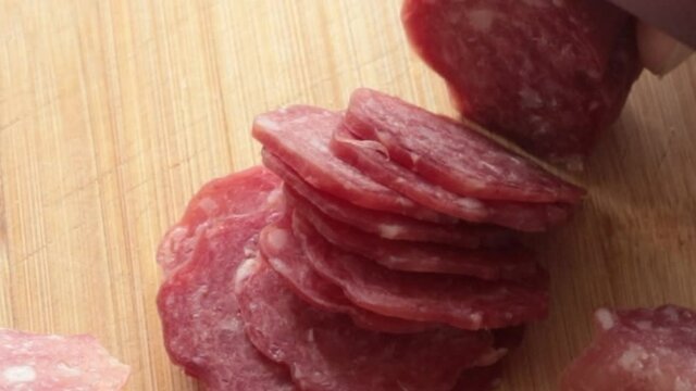 gros plan sur la coupe d'un saucisson avec un couteau