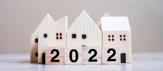 2022 Happy New Year with house model on table wooden background. Banking, real estate, investment,...