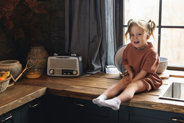 Fototapeta na wymiar Little preschool girl sitting at the kitchen table and smiling