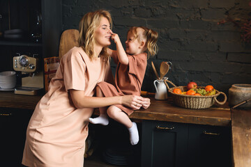 Portrait of a young mom and preschool daughter in the kitchen. Spending time with your family.