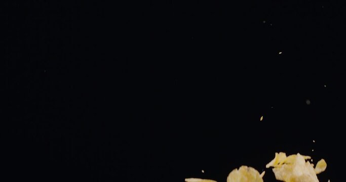 Natural potato chips rise and fall against a black background. Slow Motion 300 fps Blackmagic Ursa Pro G2.