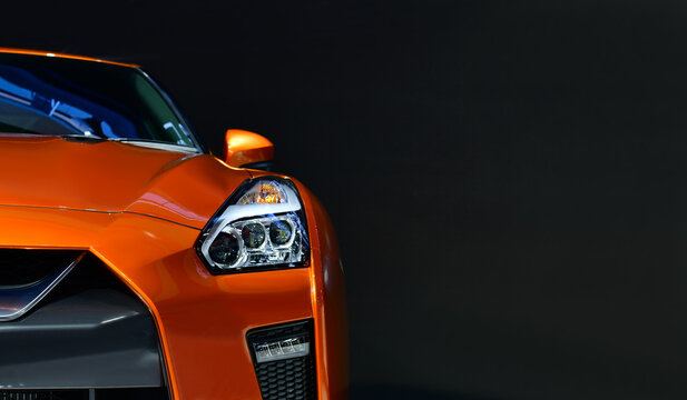 Orange modern car headlights on black background, copy space	